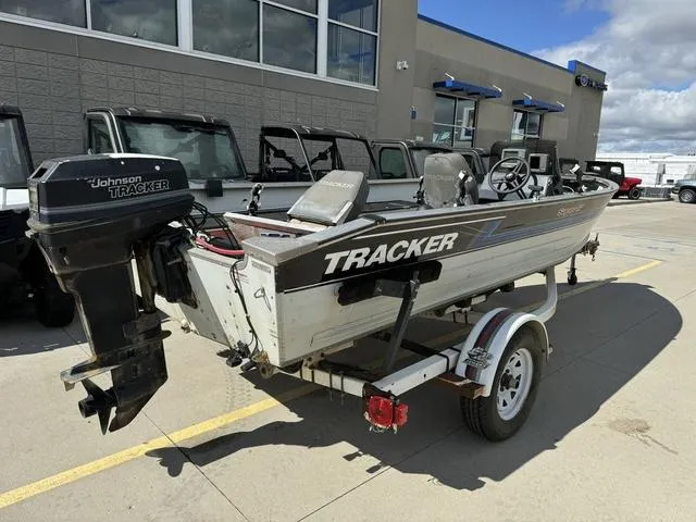 Slide: The Image of 1992 Tracker Super 17 Pro boat with Johnson motor on trailer, parked outside dealership. - 3