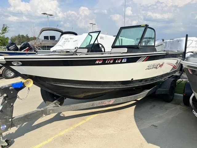 Slide: The Image of 2020 Alumacraft Trophy 185 boat on trailer, parked outdoors under a cloudy sky. - 3