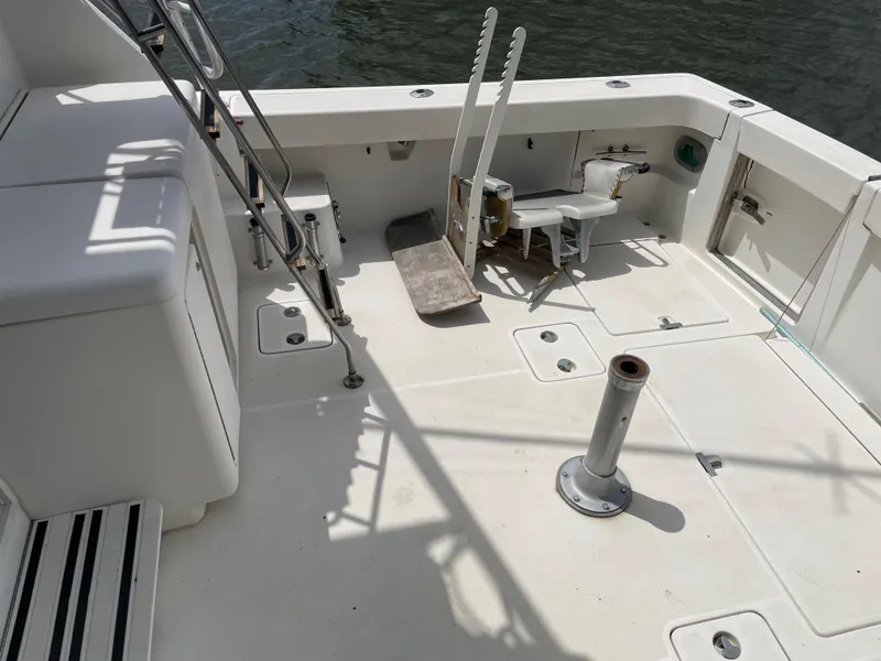 Slide: The Image of 1990 Tiara Yachts 4300 Convertible deck with fishing chair and ladder, docked by water. - 18