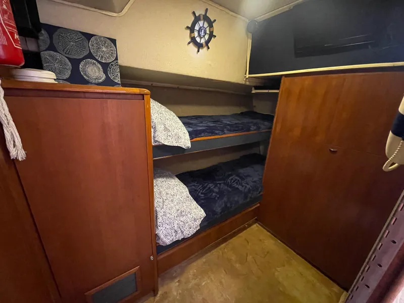 Slide: The Image of 1990 Tiara Yachts 4300 Convertible cabin with wooden bunk beds and nautical decor. - 23