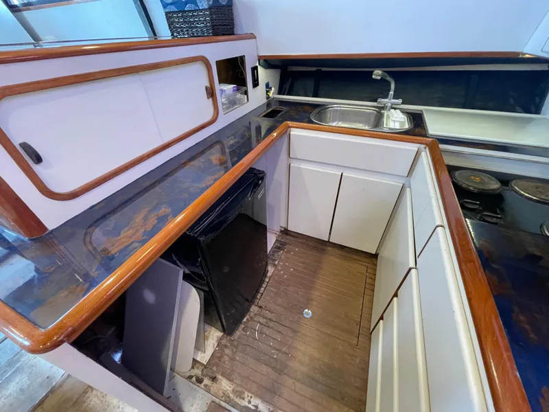 Slide: The Image of 1990 Tiara Yachts 4300 Convertible kitchen with wood accents, sink, and compact fridge. - 24