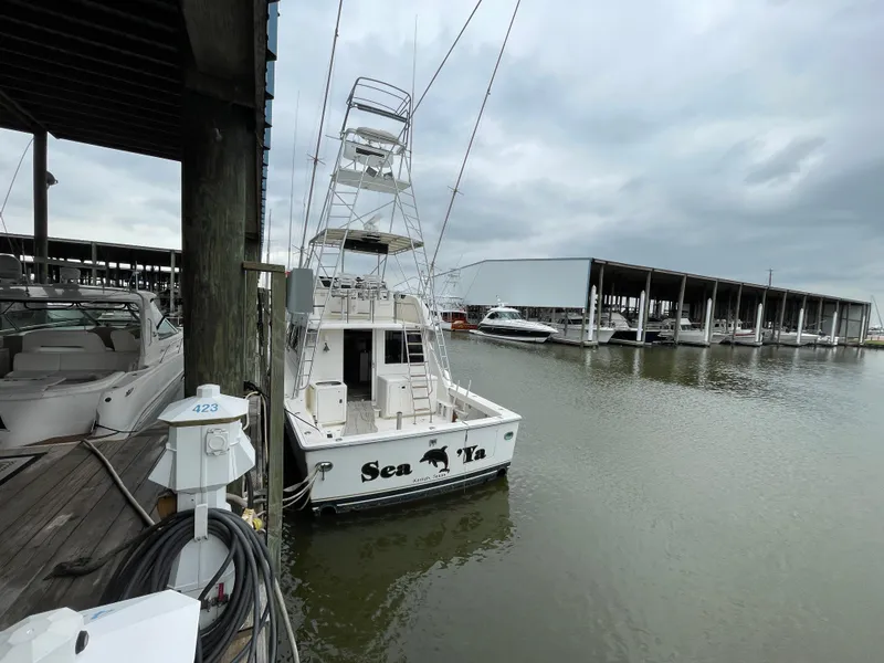 Slide: The Image of 1990 Tiara Yachts 4300 Convertible docked at marina under cloudy skies. - 4