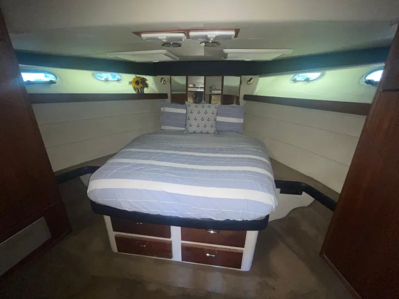 Slide: The Image of 1992 Bayliner 4588 Pilothouse bedroom with striped bedding and porthole windows. - 25