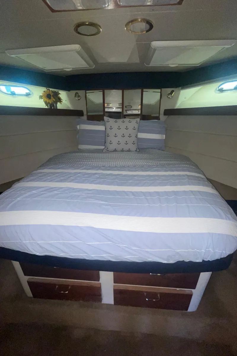 Slide: The Image of 1992 Bayliner 4588 Pilothouse bedroom with striped bedding and under-bed storage. - 26