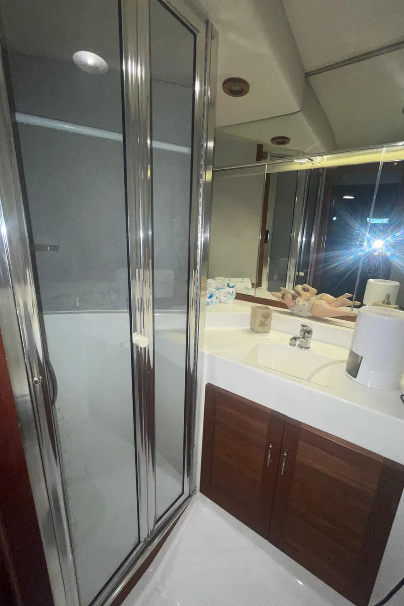 Slide: The Image of 1992 Bayliner 4588 Pilothouse bathroom with shower, mirror, and wooden cabinets. - 27