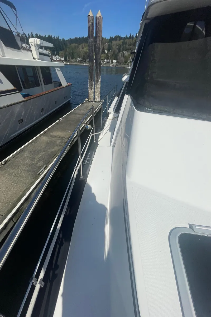 Slide: The Image of 1992 Bayliner 4588 Pilothouse yacht docked at marina, side view with clear sky. - 4