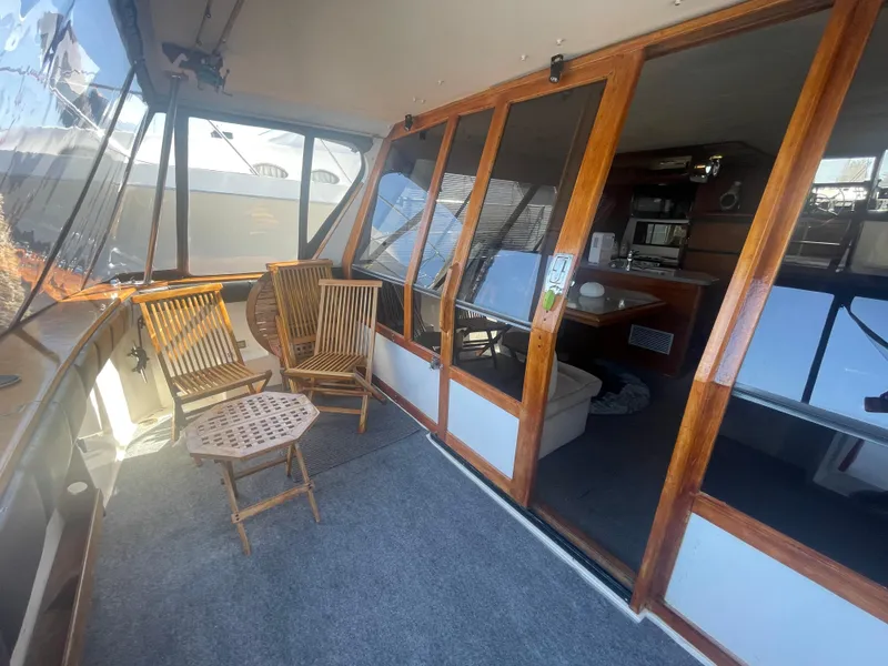 Slide: The Image of 1992 Bayliner 4588 Pilothouse yacht interior with wooden chairs and glass doors. - 6