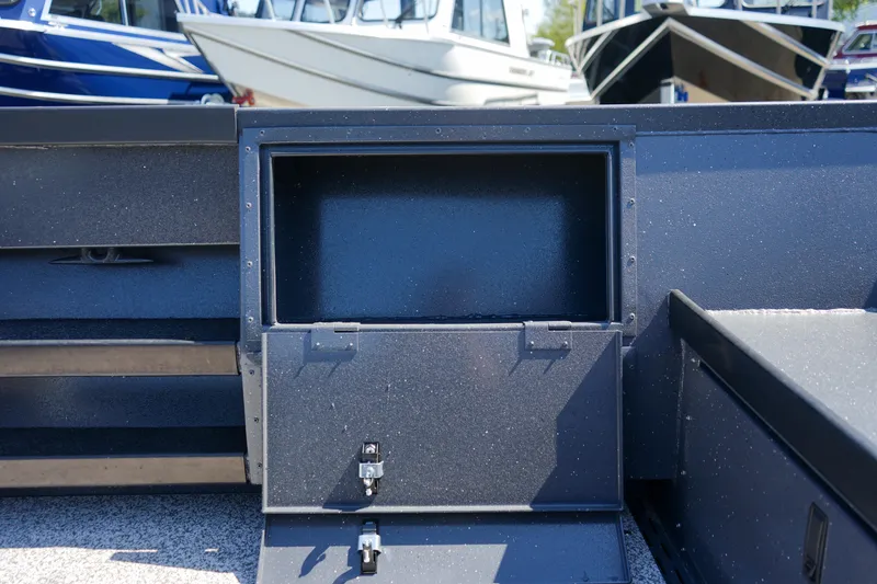 Slide: The Image of 2025 Alumaweld Columbia 23 boat storage compartment, open with visible latches, in a marina setting. - 9