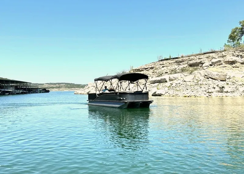 Slide: The Image of 2020 Avalon Catalina 2585 VRB pontoon boat on a serene lake with rocky shoreline. - 11