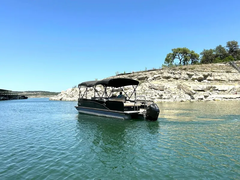 Slide: The Image of Avalon Catalina 2585 VRB pontoon boat on a serene lake with rocky shoreline. - 18