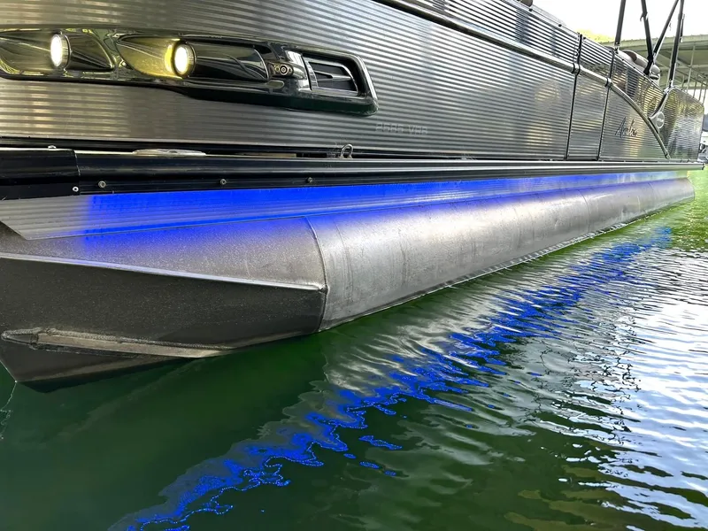 Slide: The Image of 2020 Avalon Catalina 2585 VRB pontoon boat with blue LED lights reflecting on water. - 47