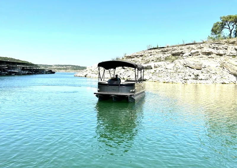 Slide: The Image of 2020 Avalon Catalina 2585 VRB pontoon boat on serene lake with rocky shoreline. - 9