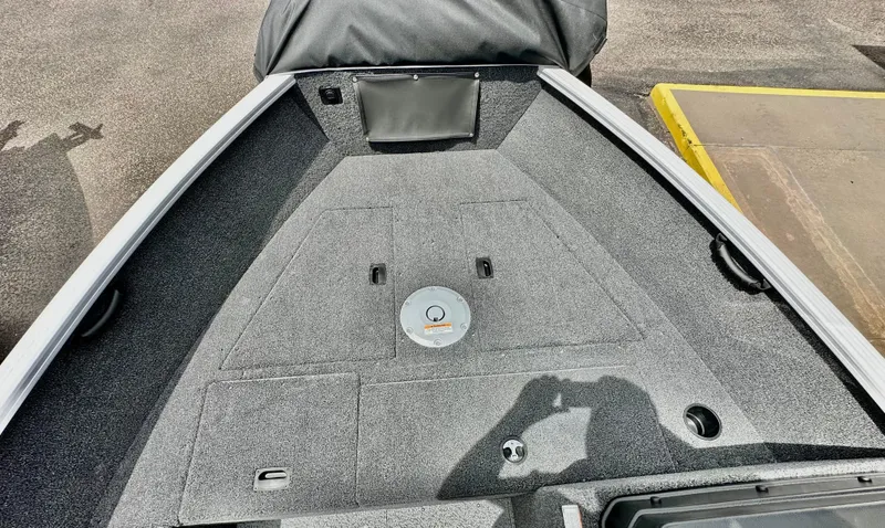 Slide: The Image of 2025 Lund 1650 Rebel XL Sport boat deck with gray carpeting and storage compartments. - 13