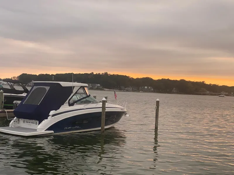 Slide: The Image of 2023 Regal 33 Sport boat docked at sunset on a calm lake. - 2