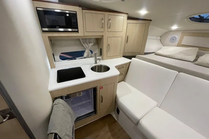Slide: The Image of 2023 Regal 33 Express interior with kitchenette, microwave, sink, and seating area. - 24