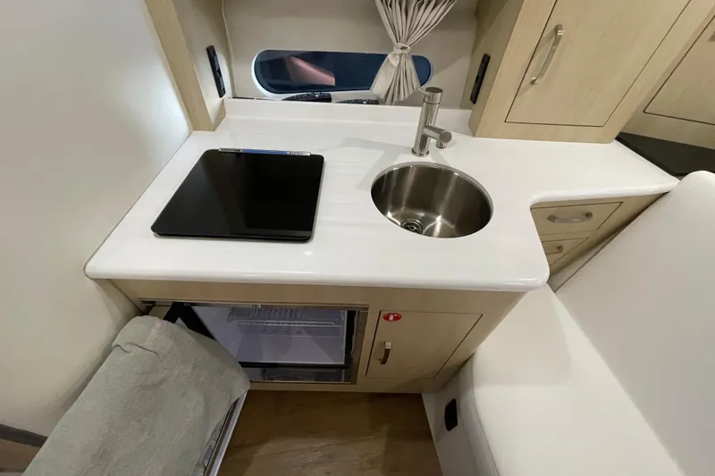 Slide: The Image of 2023 Regal 33 Express yacht interior kitchen with sink, stove, and mini fridge. - 25