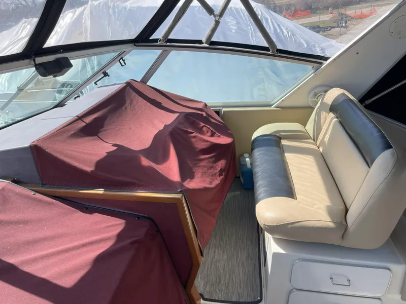 Slide: The Image of 1990 Sea Ray 390 Express Cruiser interior with covered controls and beige seating. - 17