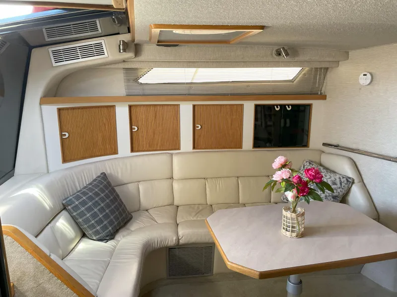 Slide: The Image of 1990 Sea Ray 390 Express Cruiser interior with beige seating, table, and floral centerpiece. - 23