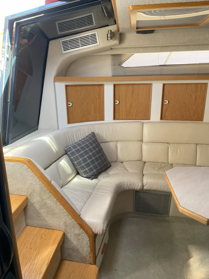Slide: The Image of 1990 Sea Ray 390 Express Cruiser interior with beige seating and wooden accents. - 24