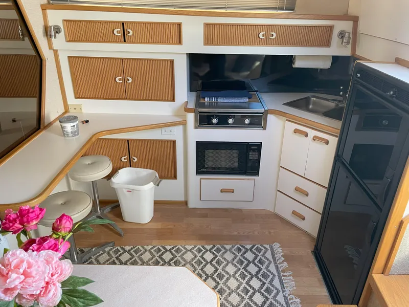 Slide: The Image of 1990 Sea Ray 390 Express Cruiser kitchen with stove, fridge, and floral decor. - 25