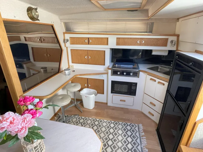 Slide: The Image of Interior of 1990 Sea Ray 390 Express Cruiser with kitchen, seating, and floral decor. - 26