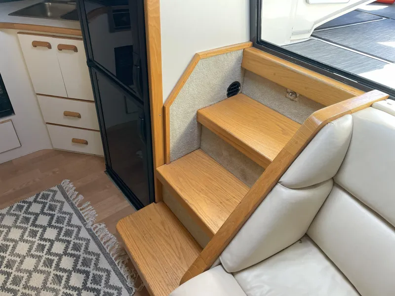Slide: The Image of Interior of 1990 Sea Ray 390 Express Cruiser with wooden stairs and modern kitchen area. - 27