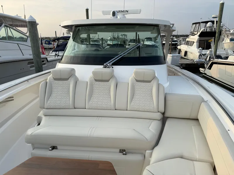 Slide: The Image of 2023 Tiara Yachts 43 LS luxury boat with plush seating at a marina. - 28