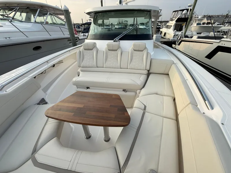 Slide: The Image of 2023 Tiara Yachts 43 LS with luxurious seating and wooden table in a marina setting. - 29