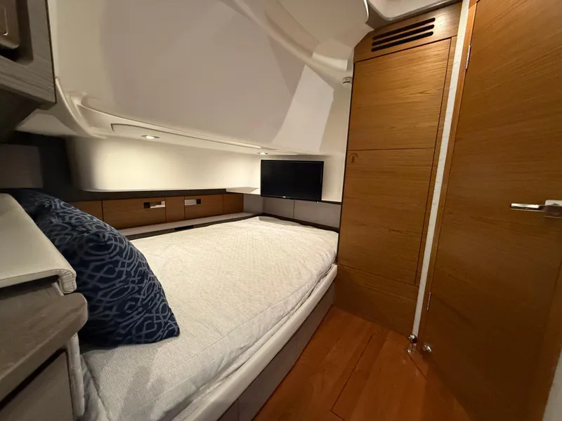 Slide: The Image of 2023 Tiara Yachts 43 LS cabin interior with bed, TV, and wooden accents. - 46
