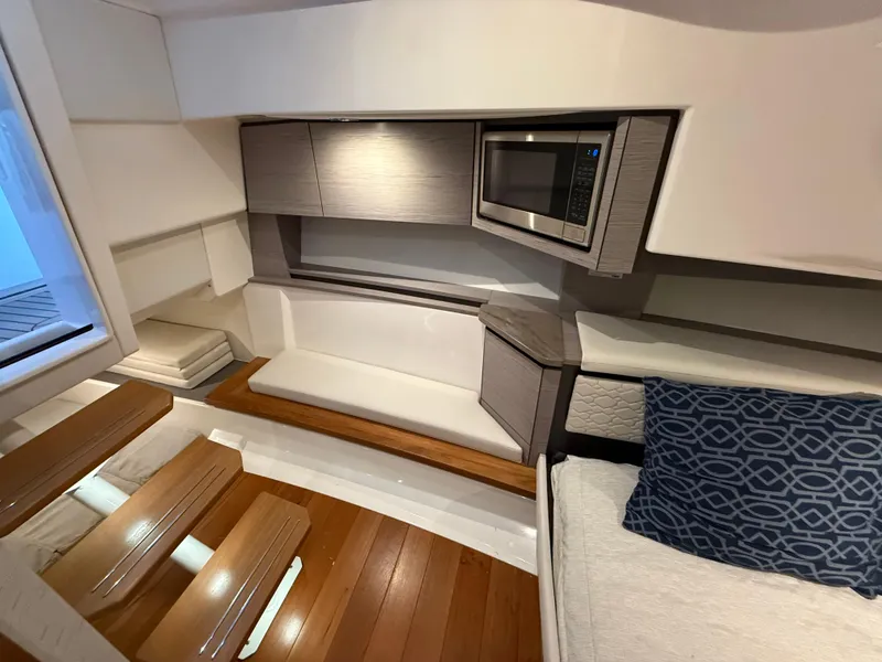 Slide: The Image of 2023 Tiara Yachts 43 LS interior with modern seating, wood flooring, and built-in microwave. - 51