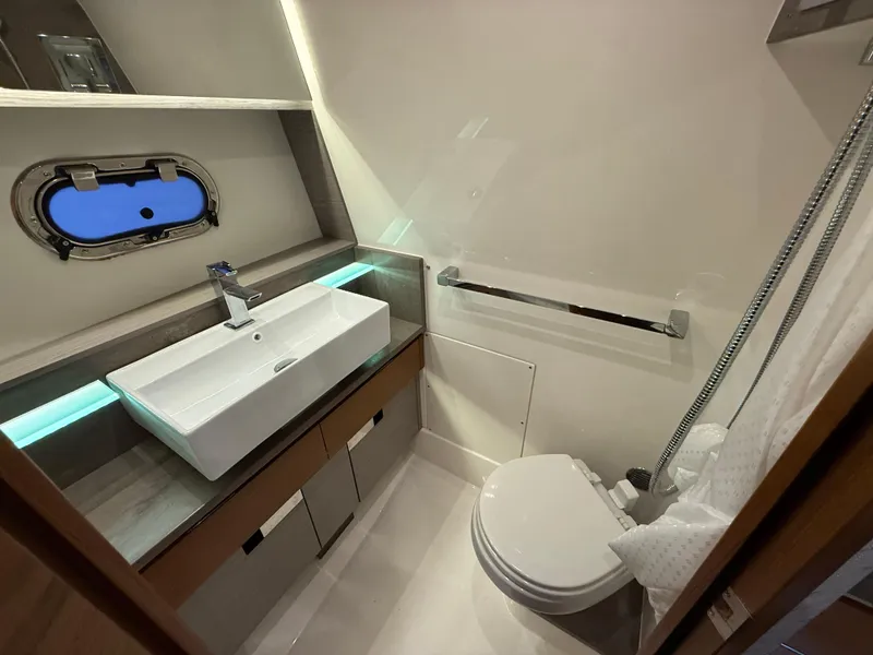 Slide: The Image of 2023 Tiara Yachts 43 LS bathroom with modern sink, toilet, and porthole window. - 55