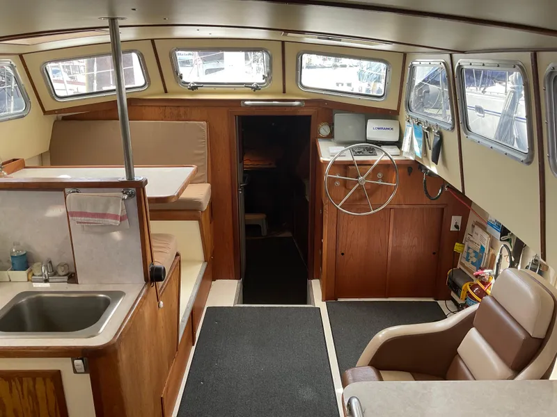 Slide: The Image of Interior of 1980 Kanter Staysail Cutter, featuring helm, seating, and kitchenette with sink. - 13