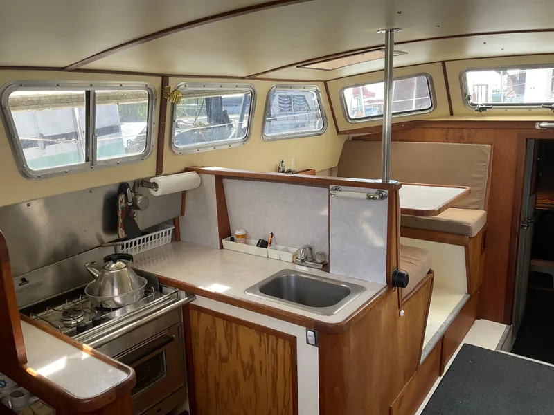 Slide: The Image of Interior of 1980 Kanter Staysail Cutter, featuring a compact kitchen and seating area. - 16