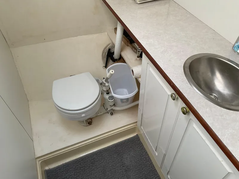 Slide: The Image of 1980 Kanter Staysail Cutter bathroom with toilet, sink, and storage cabinets. - 26