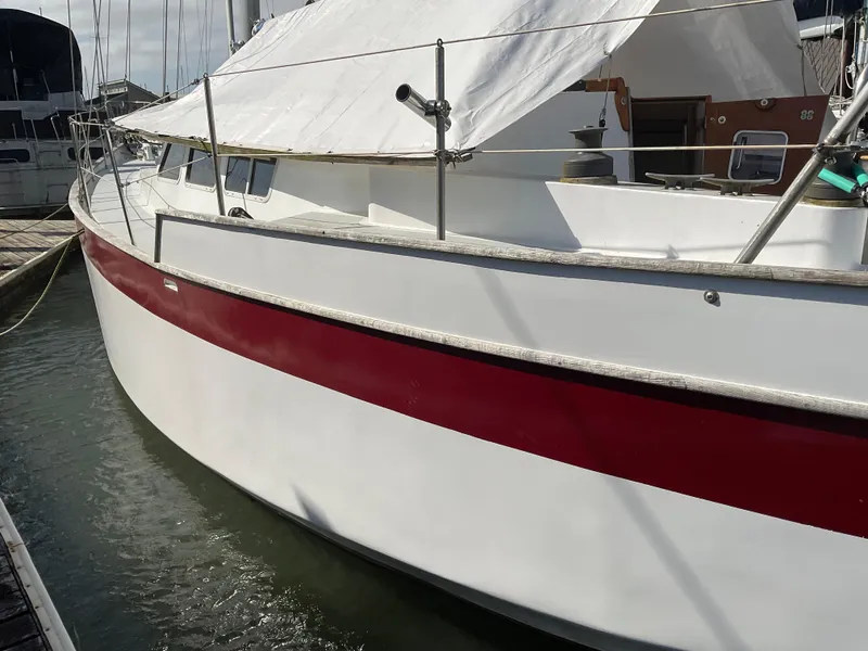 Slide: The Image of 1980 Kanter Staysail Cutter with red stripe, docked in marina. - 4