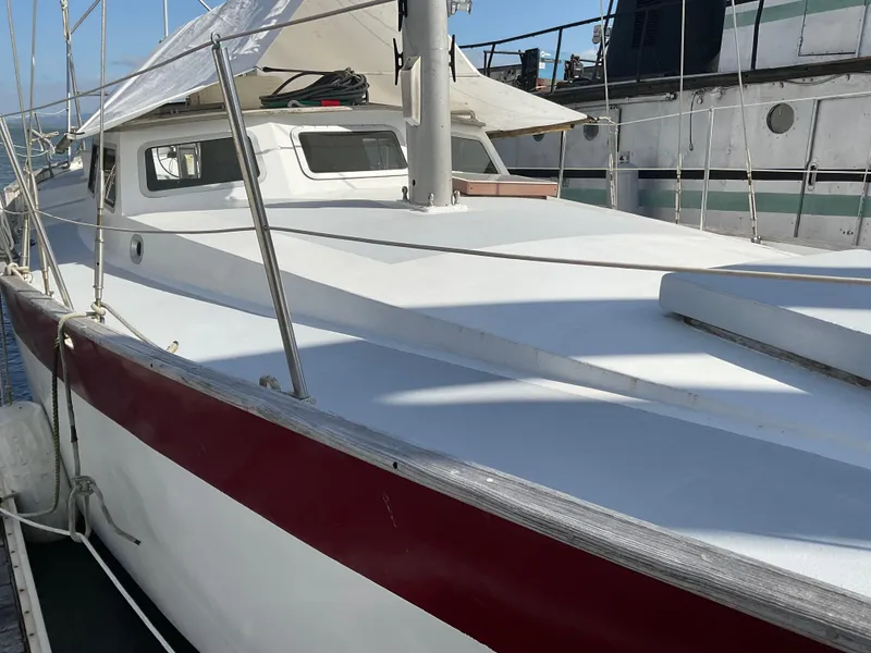 Slide: The Image of 1980 Kanter Staysail Cutter sailboat with white and red hull, docked at marina. - 6