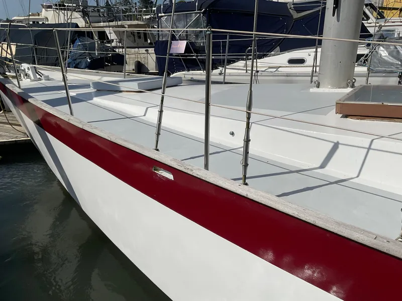 Slide: The Image of 1980 Kanter Staysail Cutter sailboat with red and white hull, docked at marina. - 7