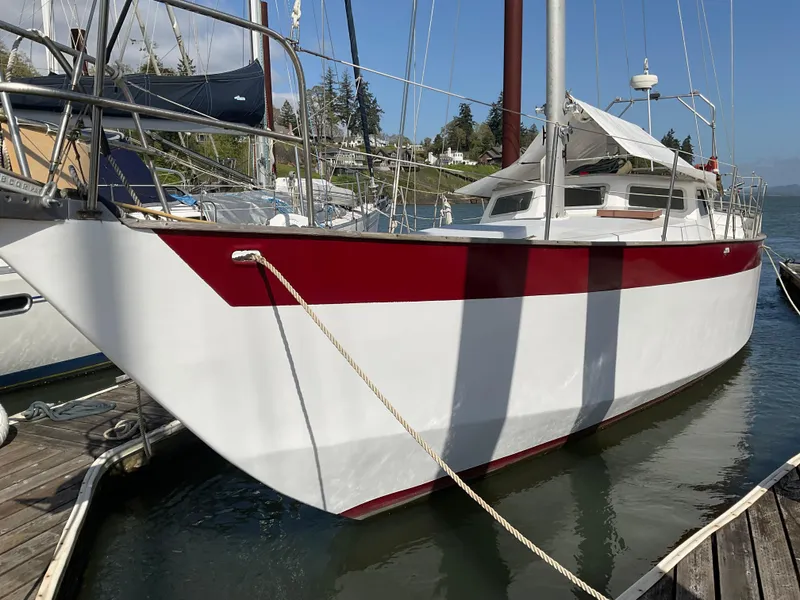 Slide: The Image of 1980 Kanter Staysail Cutter docked, featuring a red and white hull design. - 8