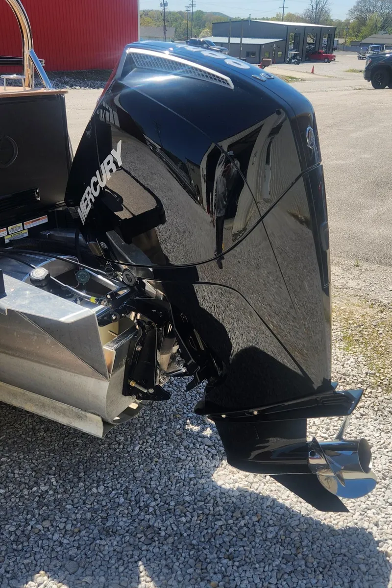 Slide: The Image of 2024 Avalon LSZ 2385 Rear Lounger with Mercury outboard engine, parked on gravel. - 11