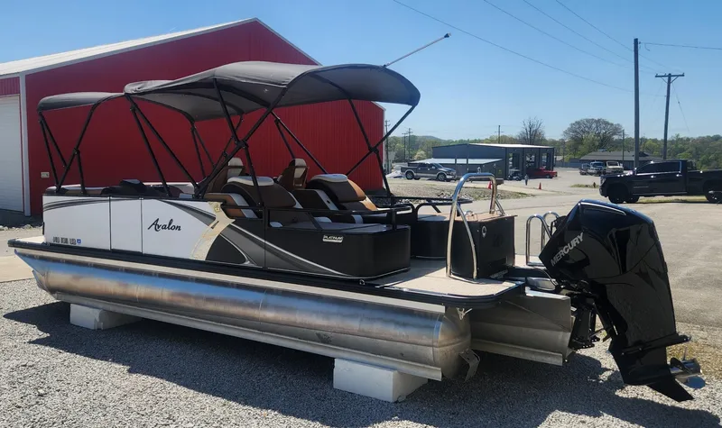 Slide: The Image of 2024 Avalon LSZ 2385 Rear Lounger pontoon boat with canopy, parked outdoors. - 2