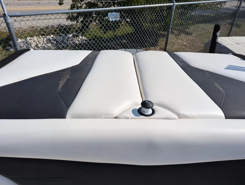 Slide: The Image of 2019 Axis A22 boat seat with white and black upholstery, near a chain-link fence. - 9