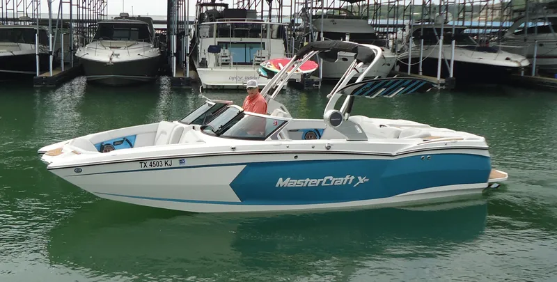 Slide: The Image of 2021 MasterCraft XStar boat on water, docked with other boats in the background. - 1