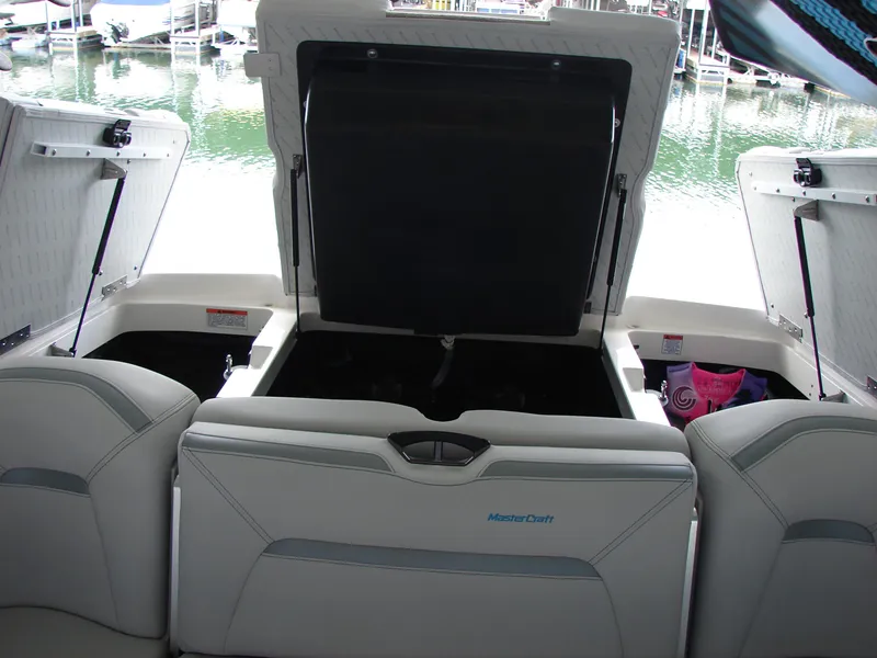 Slide: The Image of 2021 MasterCraft XStar boat interior with open storage compartments at a marina. - 12