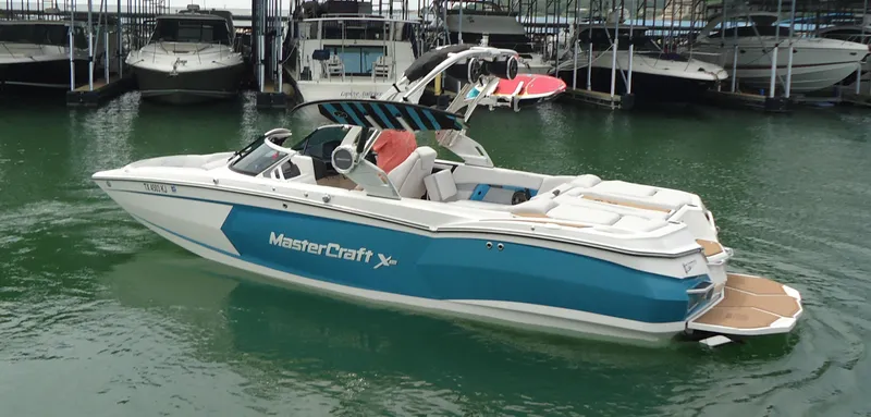 Slide: The Image of 2021 MasterCraft XStar boat in marina, featuring sleek design and vibrant blue accents. - 2