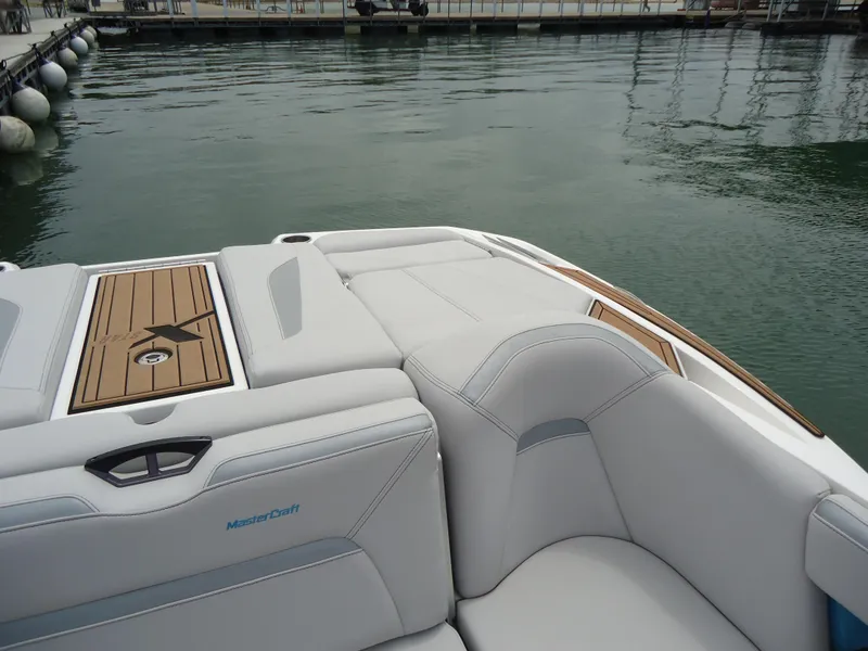 Slide: The Image of 2021 MasterCraft XStar boat interior with sleek white seating and wooden accents. - 25