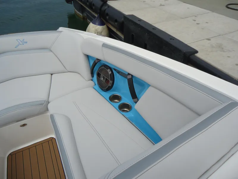 Slide: The Image of 2021 MasterCraft XStar boat interior with white seating, blue accents, and cup holders. - 26