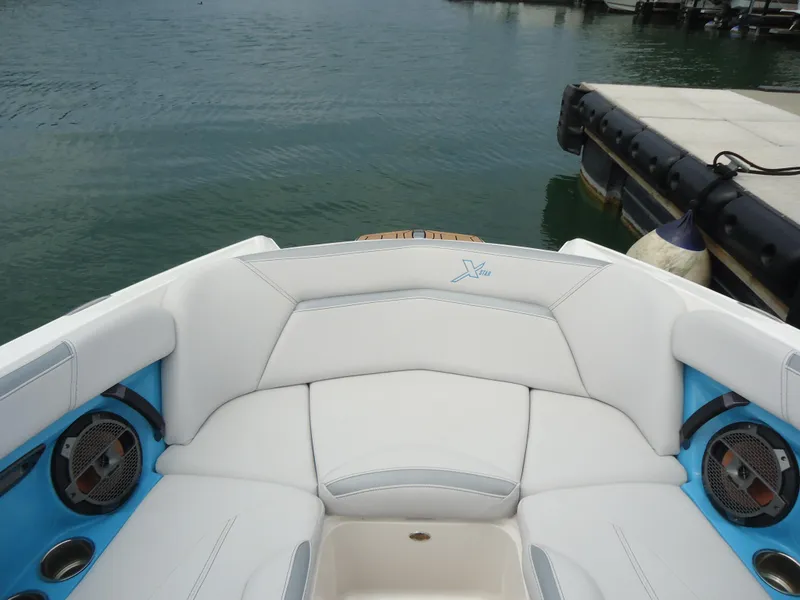 Slide: The Image of 2021 MasterCraft XStar boat interior with white seating and blue accents by the water. - 27