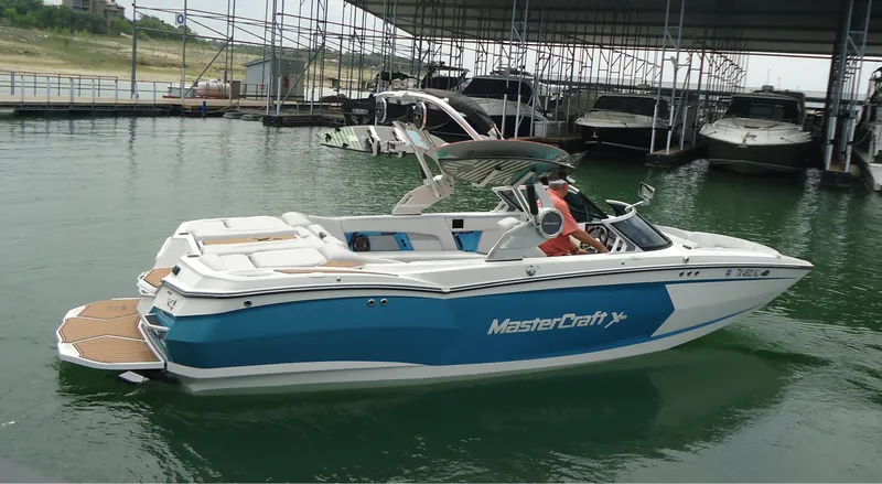 Slide: The Image of 2021 MasterCraft XStar boat docked in marina, featuring sleek blue and white design. - 3