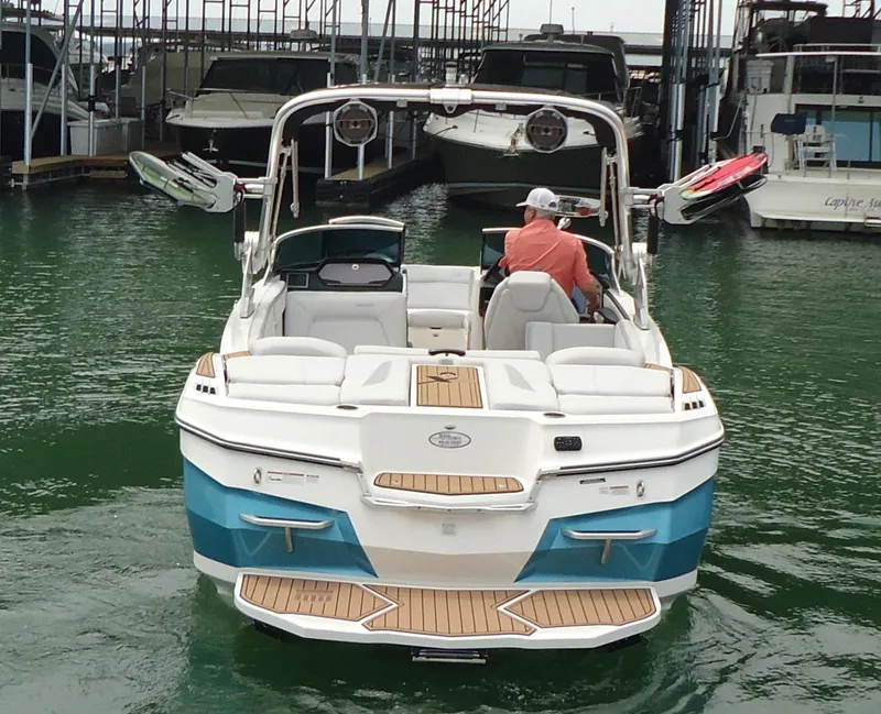 Slide: The Image of 2021 MasterCraft XStar boat in marina, rear view, with teak decking and water sports equipment. - 4