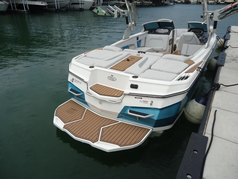 Slide: The Image of 2021 MasterCraft XStar boat docked, featuring spacious seating and teak swim platform. - 6